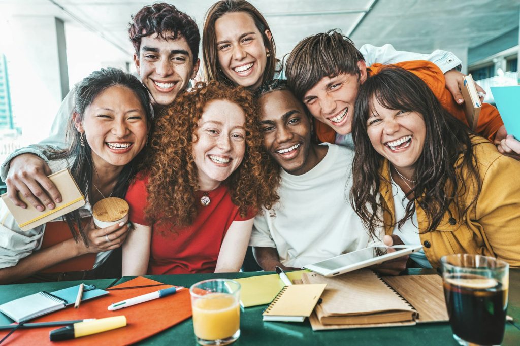 Multiracial university students sitting together at table with books and laptop